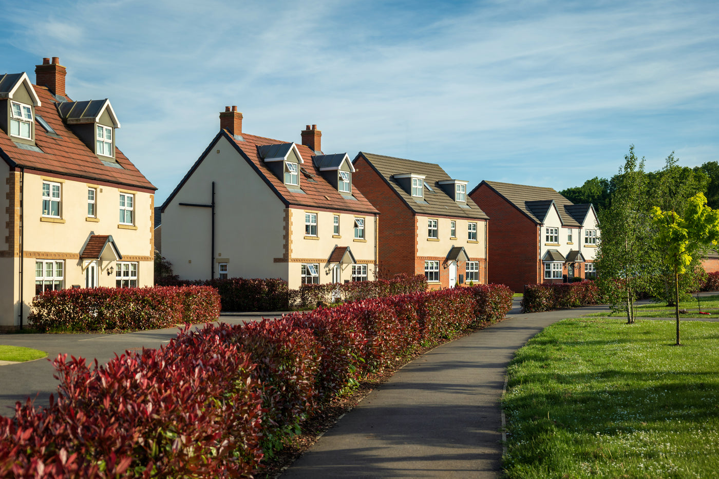 The camera looks over a tidy footpath observing a row of modern new-built homes.