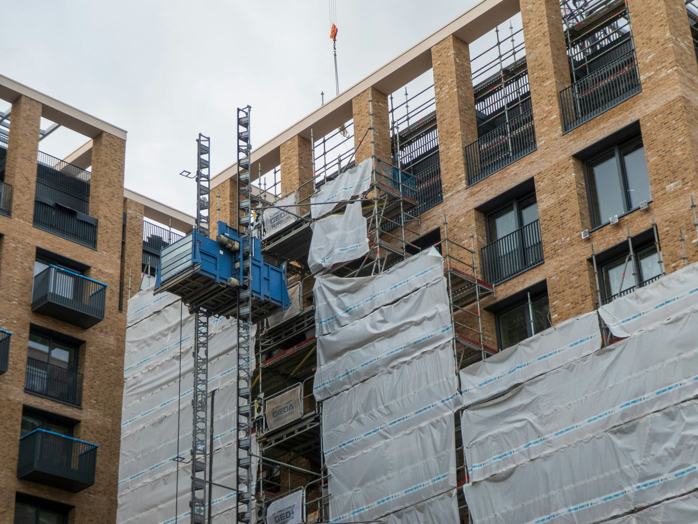 Scaffolding and a scaffold crane adorn a building undergoing works to install windows with sealant